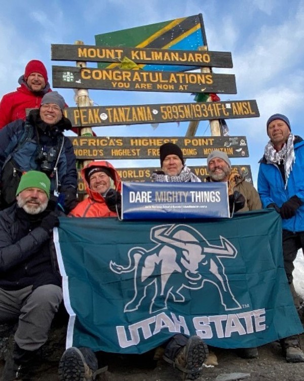 Aggies pose with a Utah State flag on top of Mount Kilimanjaro.
